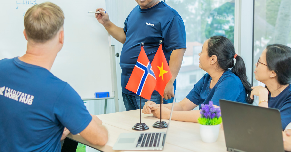 Ansatte fra Facilitated Work Hub i møte, med norske og vietnamesiske flagg som symboliserer kulturell tilpasning.